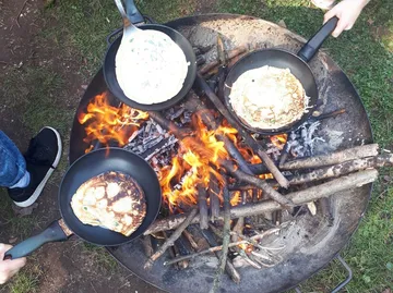 Pfannkuchen über offenem Feuer im Freien kochen.
