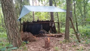 Provisorischer Unterstand mit Plane im Wald.