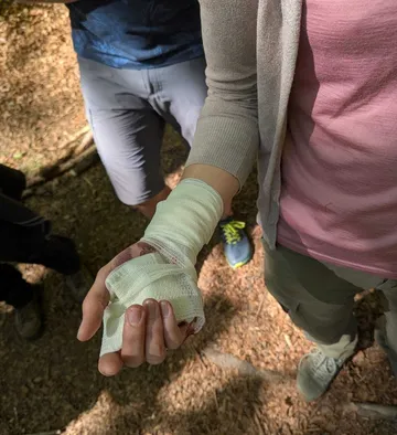 Verbandene Hand in einer Waldlichtung gehalten.