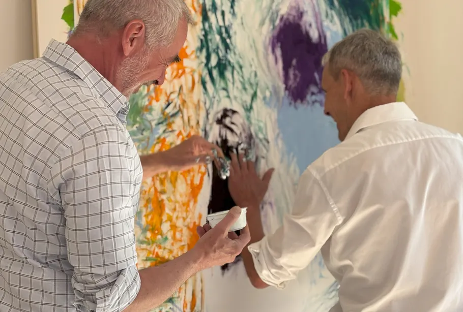 Two men painting abstract art together.
