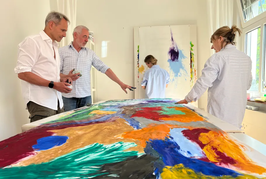 Four people discussing colorful painting indoors.