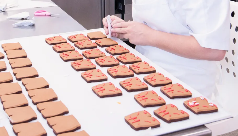 Person decorates cookies on a baking sheet.