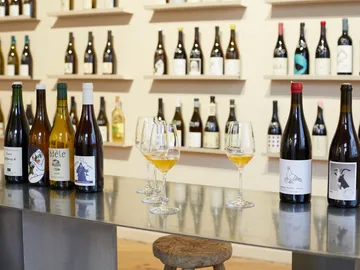 Bottled wine is on a table in front of a wall.