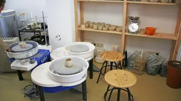 Töpferscheiben und Regale in einem Studio.