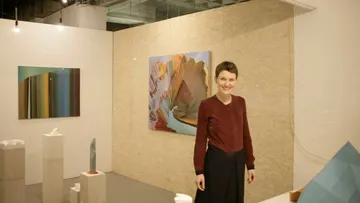 Person steht in einer Galerie mit Gemälden.