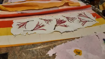 Getrocknete Blumen auf handgeschöpftem Papier, bunter Hintergrund.
