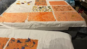 Bunte Papierbögen trocknen auf Tischen.