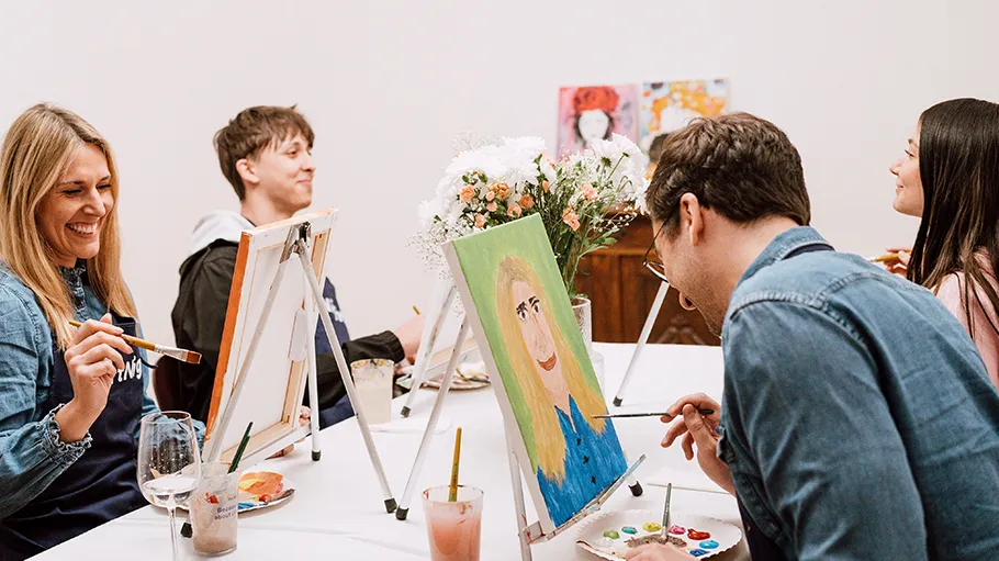 Group painting at a table with easels.