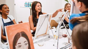 Frauen lachen und malen in einem Malkurs.