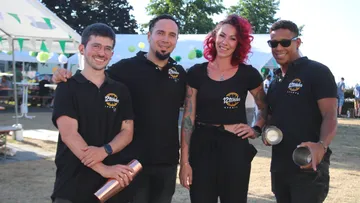 Four people smiling outdoors at an event.