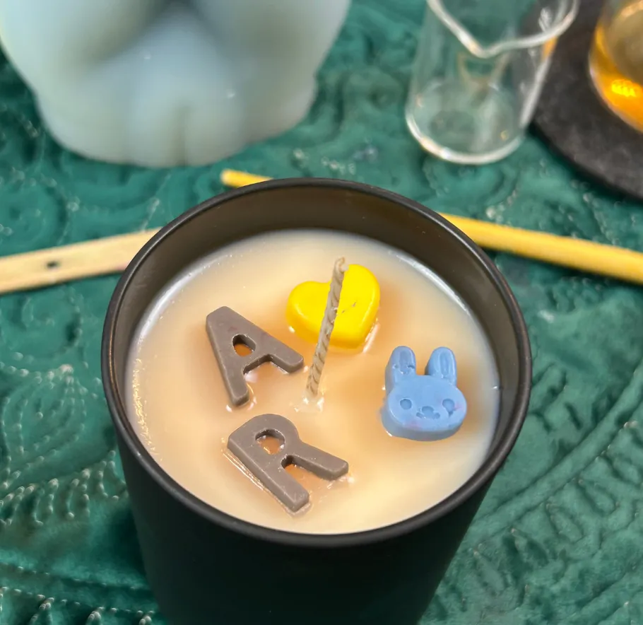 Candle with decorative letters and shapes.