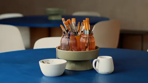 Paintbrushes in jars on a blue table.