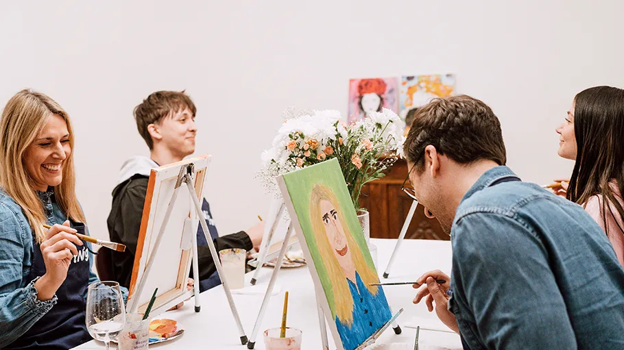 People painting at a table, smiling, indoors.