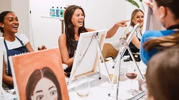Women laughing and painting at workshop.