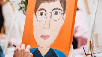 Portrait painting with orange background, being painted.