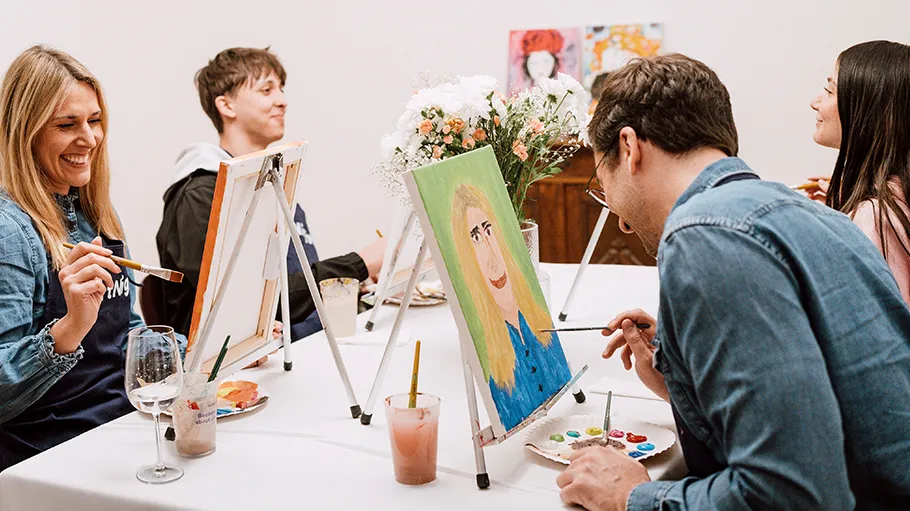 People painting at a table with canvases.