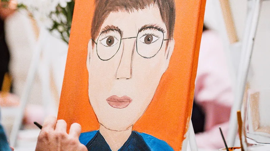 Person painting a portrait on easel indoors.