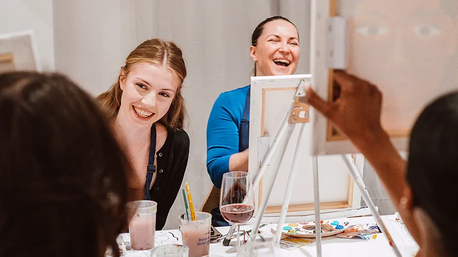 People laughing and painting in a class.