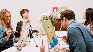 People painting at a table, enjoying themselves.