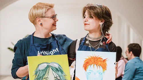 Zwei Personen in Kunstkurs halten Gemälde.