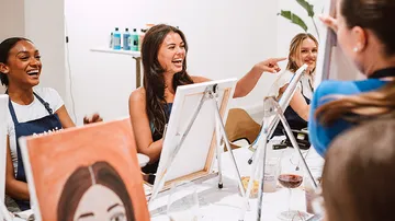 Frauen lachen und malen im Studio.