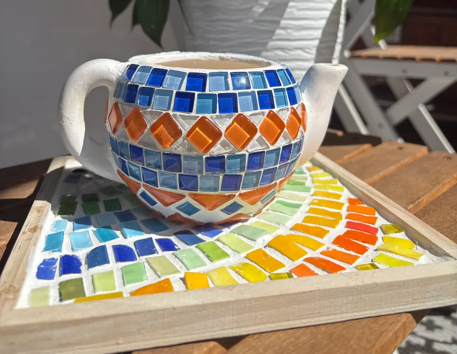 Mosaic teapot on colorful tiled tray.