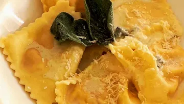 Ravioli with sage and cheese on plate.