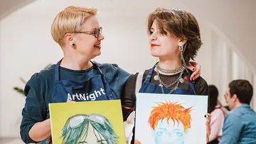 Two artists showing portraits in an art studio.