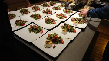 Plates with salad prepared on a kitchen counter.