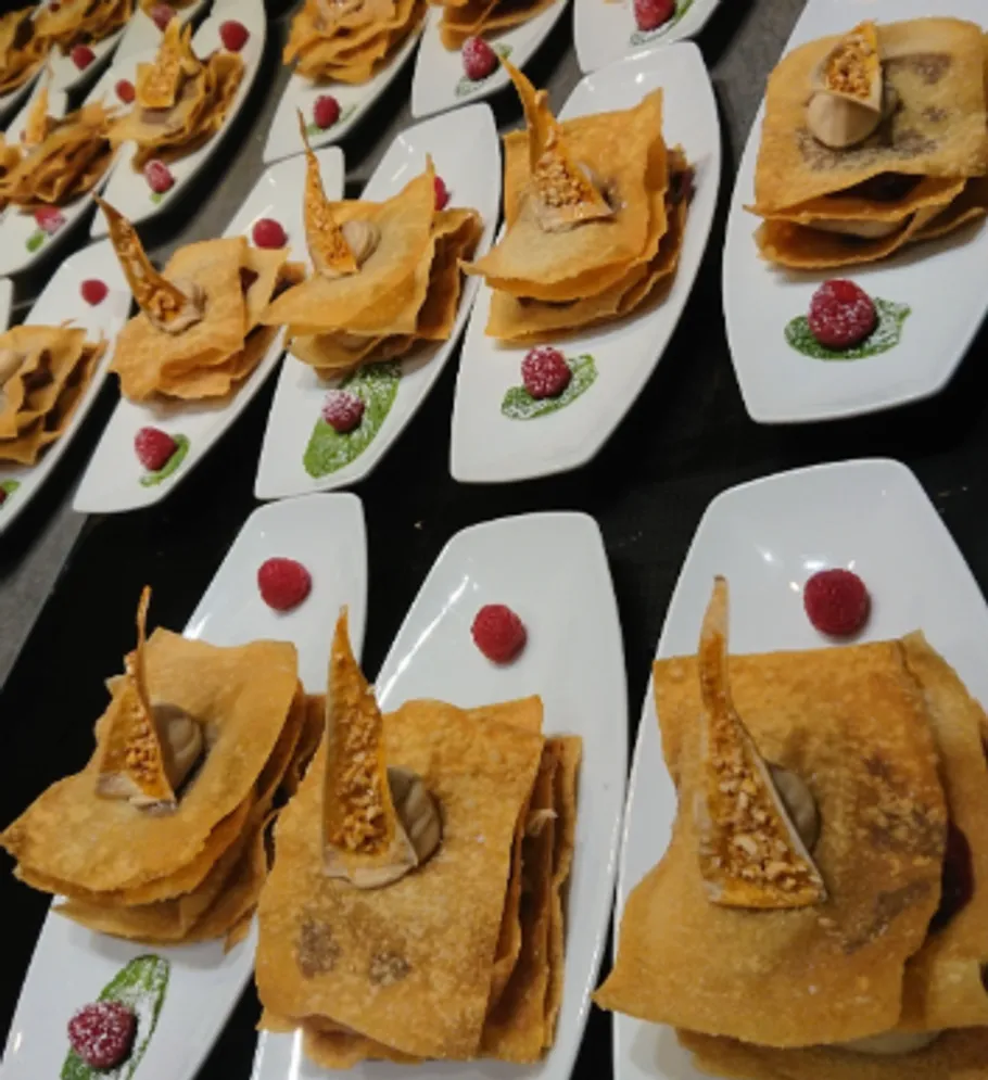 Geschichtete Desserts mit Himbeeren auf weißen Tellern.