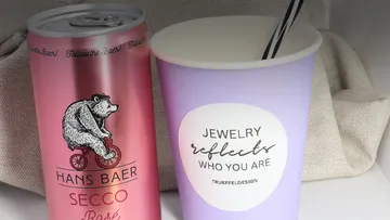Can of rosé and cup on a table.