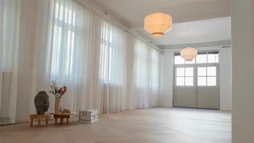 Geräumiger Raum mit Vorhängen und Pendelleuchten.