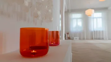 Orange glass candle holders in bright room.