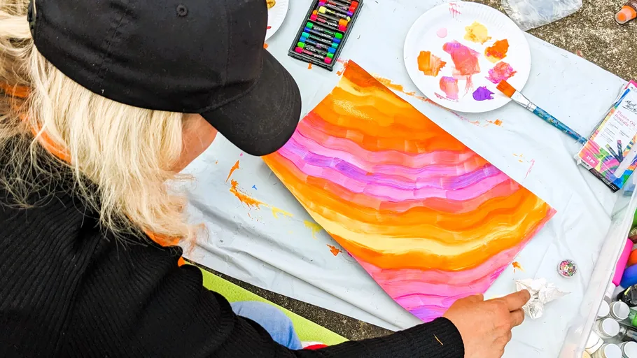 Person malt bunte abstrakte Kunst im Freien.