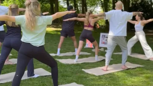 Personen praktizieren Yoga im Freien auf Gras.