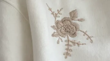 Nahaufnahme einer Stickblume auf weißem Stoff.