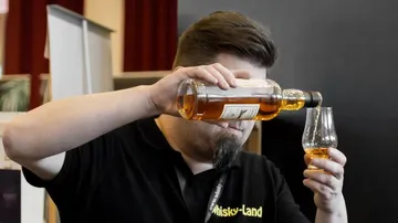 Mann gießt Whisky in Glas bei Veranstaltung.