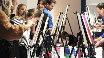 Personen malen auf Leinwänden in einem Workshop.