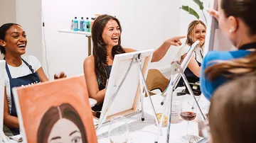 People laughing and painting in art class.