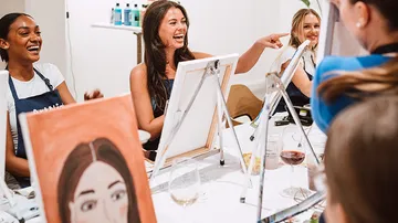 Frauen lachen und malen im Kunstkurs.