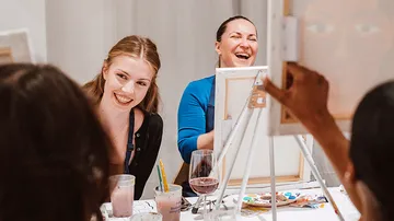 People laughing while painting at a table.