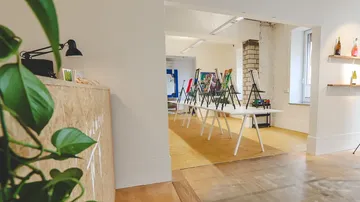 Kunststudio mit Staffeleien auf Tischen.