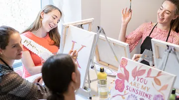 Women painting and laughing at a table.