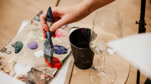 Hand painting with brush near wine glass.