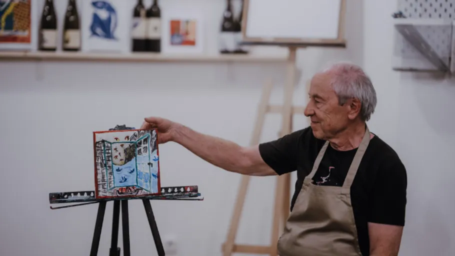 Mann zeigt buntes Kunstwerk im Studio.