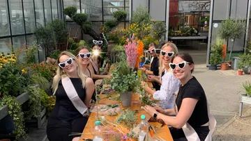 Women wearing heart glasses doing crafts outdoors.