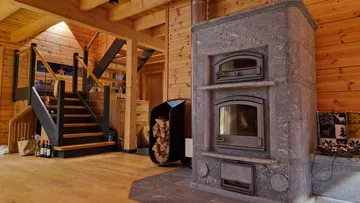 Steinofen in holzverkleidetem Raum mit Treppe.