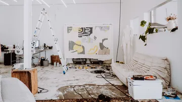 Atelier mit Sofa, Leiter und abstraktem Gemälde.