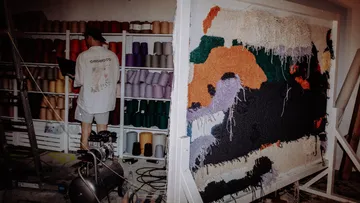Person weaving colorful tapestry in workshop.