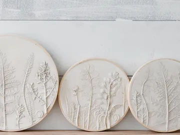 Three round relief plates with plant prints on the wall.